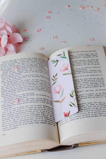 Aquarell-Lesezeichen mit rosa Tulpen und grünen Blättern in einem aufgeschlagenen Buch, umgeben von rosa Blütenblättern und buntem Konfetti