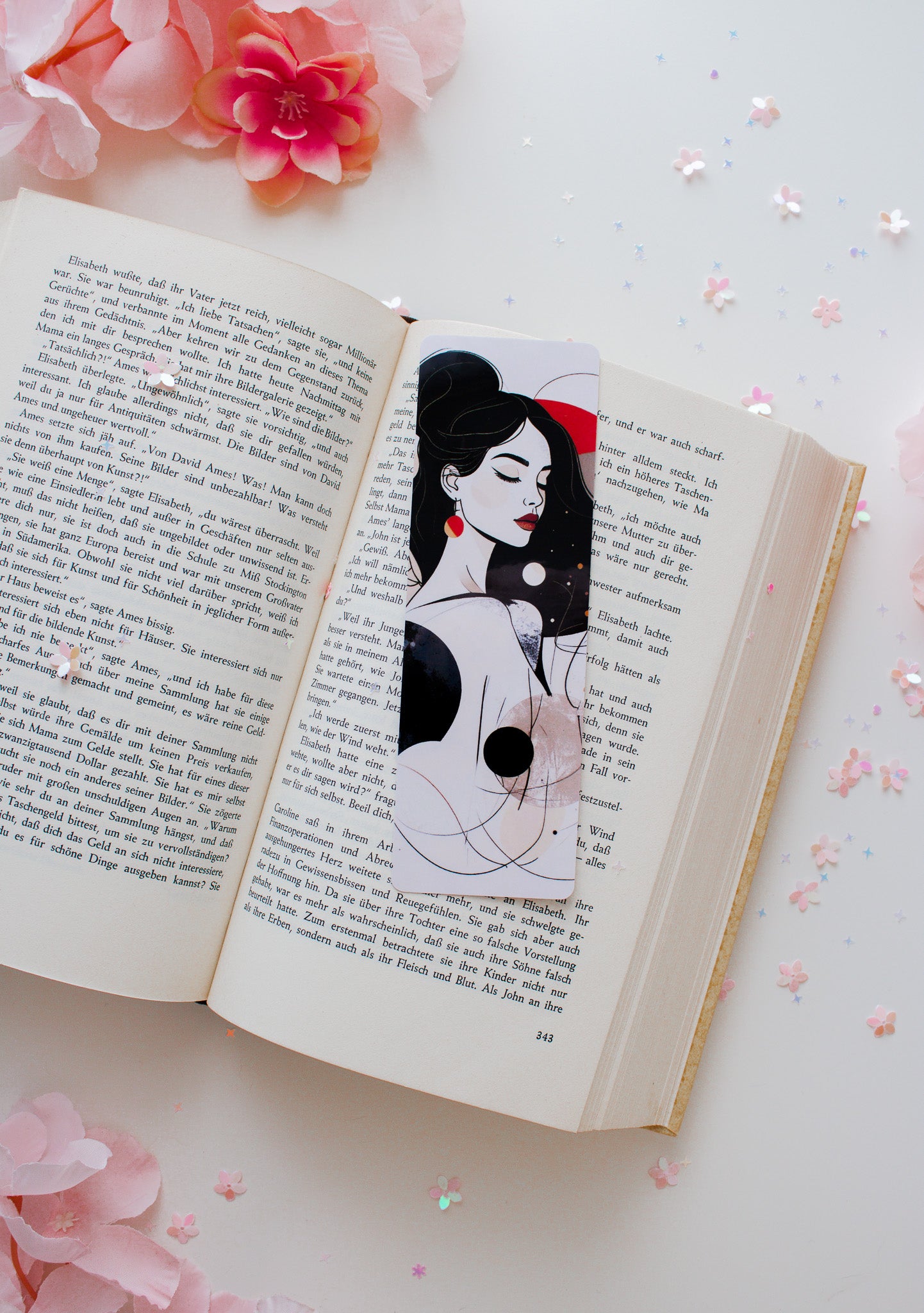 Doppelseitiges Glossy-Lesezeichen mit minimalistischer Frauenillustration, rote Akzente, schwarzes Oberteil, auf aufgeschlagenem Buch mit Konfetti