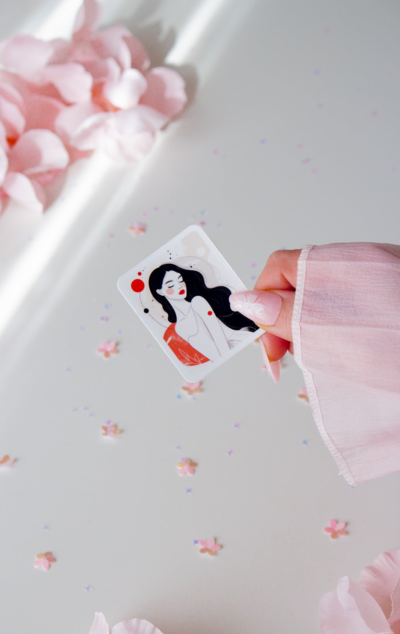 Eleganter Vinyl Sticker Celestial Woman, Frauenillustration mit schwarzen Haaren, roten Lippen und rotem Punkt, in der Hand gehalten vor Sternenkonfetti