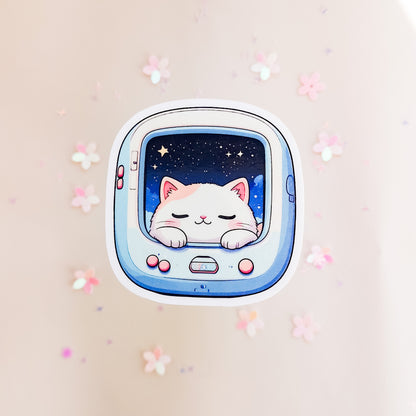 Kawaii Space Cat Sticker, schlafendes weißes Kätzchen im hellblauen Retro-Pet-Gerät mit Sternenhimmel und pinken Knöpfen, vor Blütenkonfetti