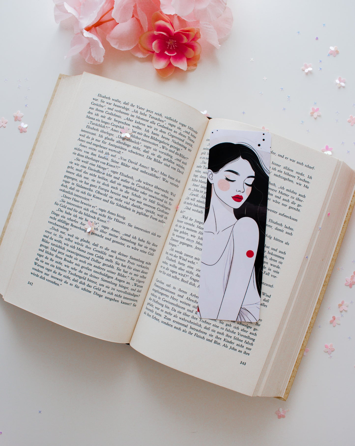 Doppelseitiges Glossy-Lesezeichen mit eleganter Frauenillustration, schwarze lange Haare, rote Lippen, roter Punkt, auf aufgeschlagenem Buch mit rosa Blüten