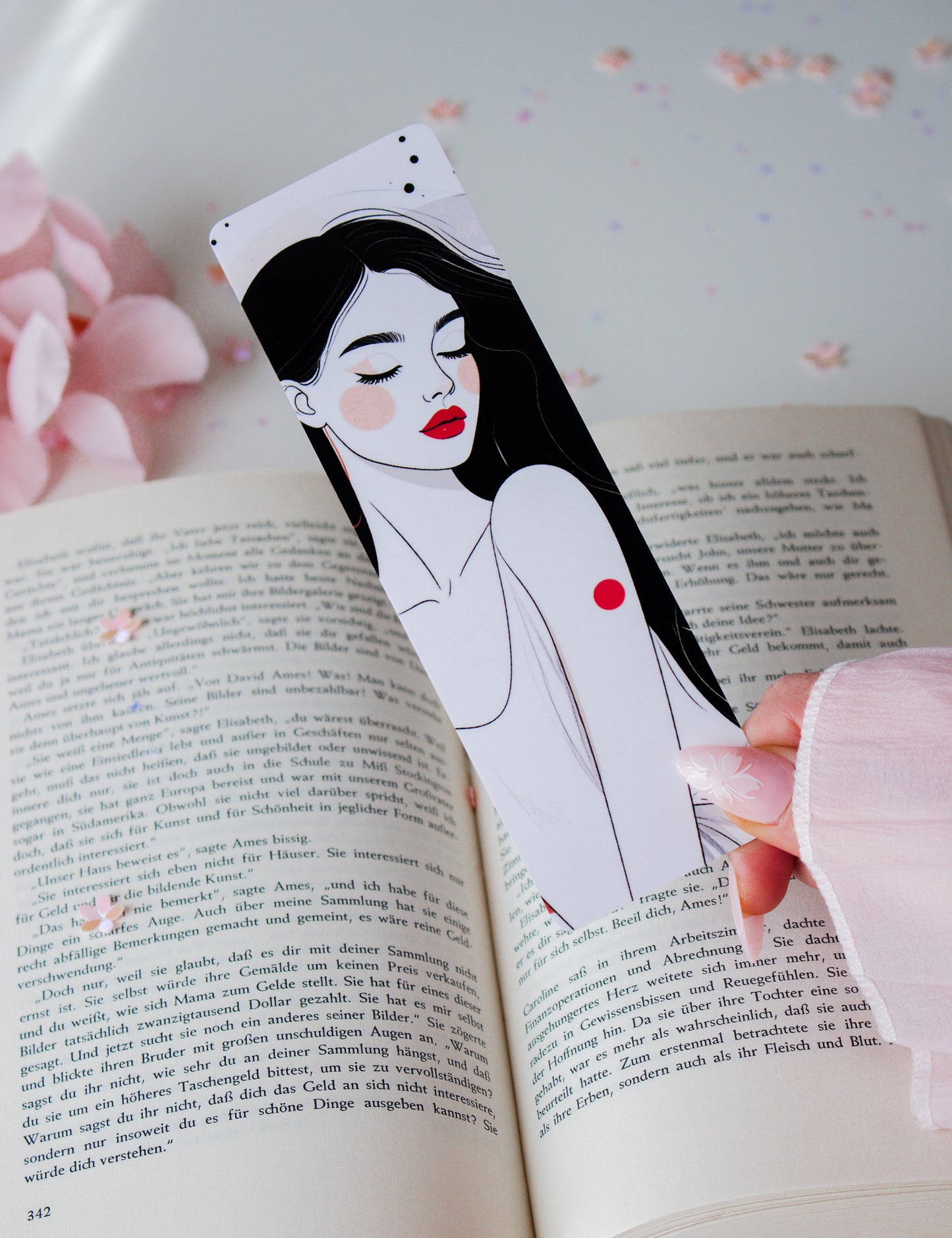 Doppelseitiges Lesezeichen mit minimalistischer Line-Art-Frau, rote Lippen, schwarze Haare, gehalten vor aufgeschlagenem Buch mit rosa Blüten