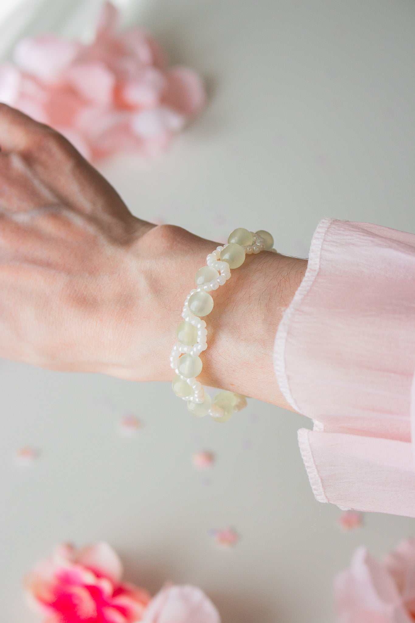 Perlenarmband Grün mit weißen Acrylperlen am Handgelenk – helle Studioaufnahme