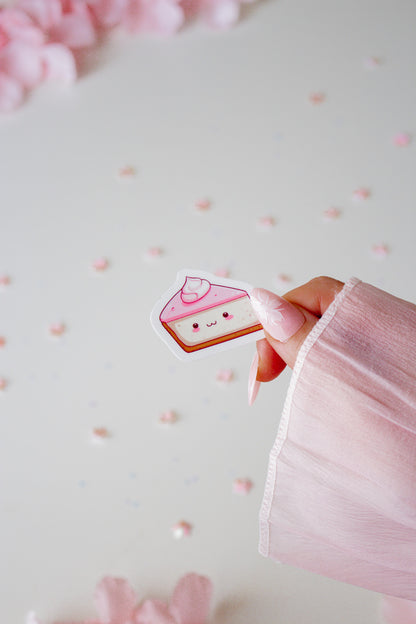 Kawaii Red Velvet Cake Sticker, gehalten von einer Hand vor hellrosa Hintergrund mit Blütenblättern