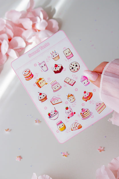 Kawaii Vinyl Sticker Bogen Sweet Taste Glossy, 20 niedliche Food-Motive mit Kawaii-Gesichtern in Pastellrosa, in der Hand gehalten vor rosa Blüten