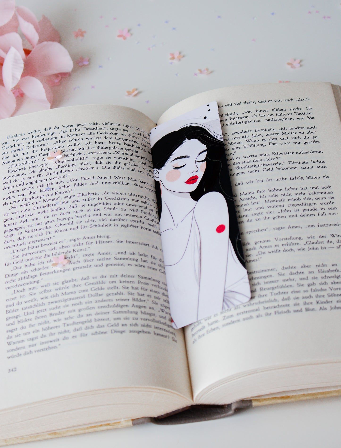 Laminiertes Lesezeichen mit eleganter Line-Art-Illustration einer Frau mit roten Lippen und schwarzen Haaren, auf aufgeschlagenem Buch
