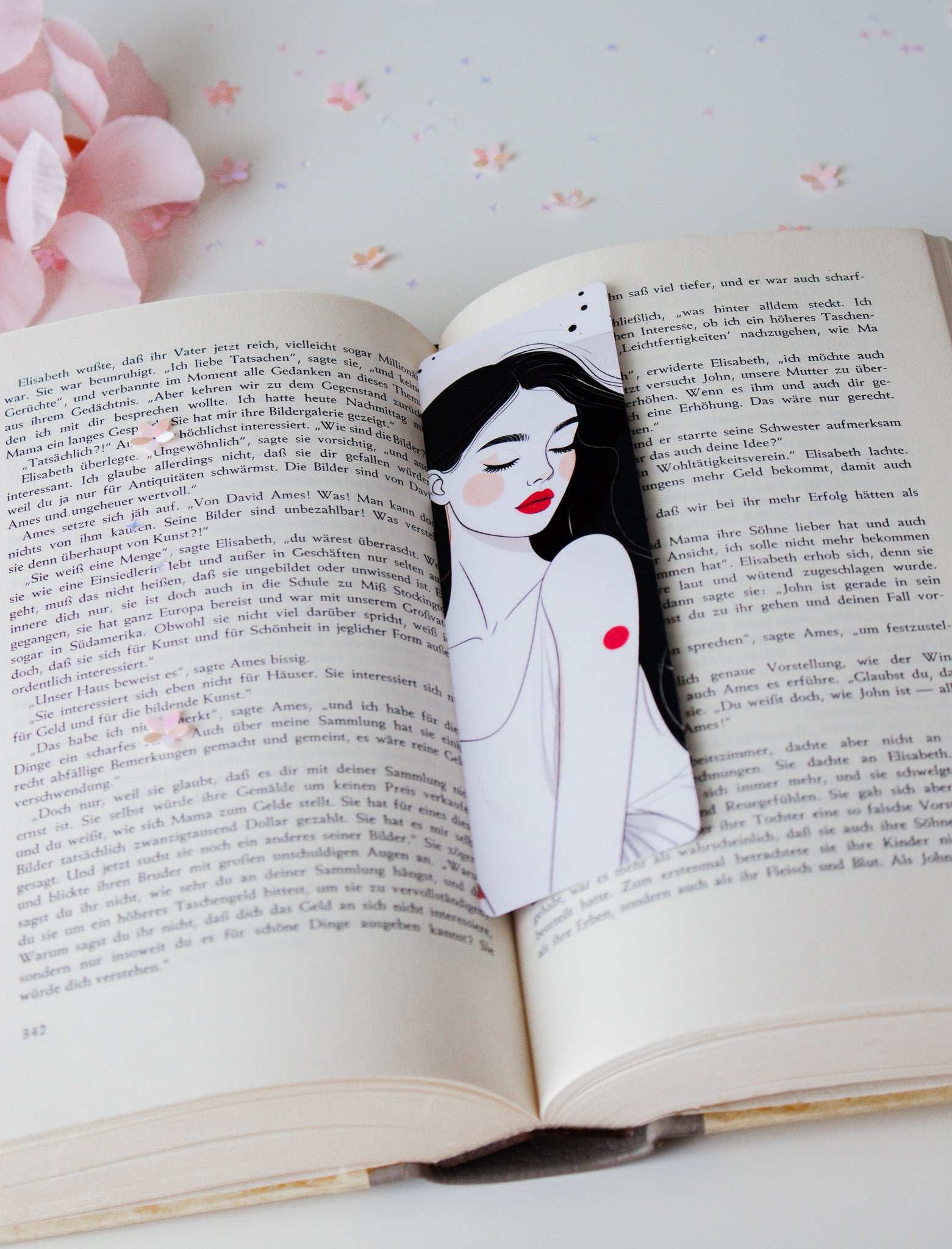 Laminiertes Lesezeichen mit eleganter Line-Art-Illustration einer Frau mit roten Lippen und schwarzen Haaren, auf aufgeschlagenem Buch