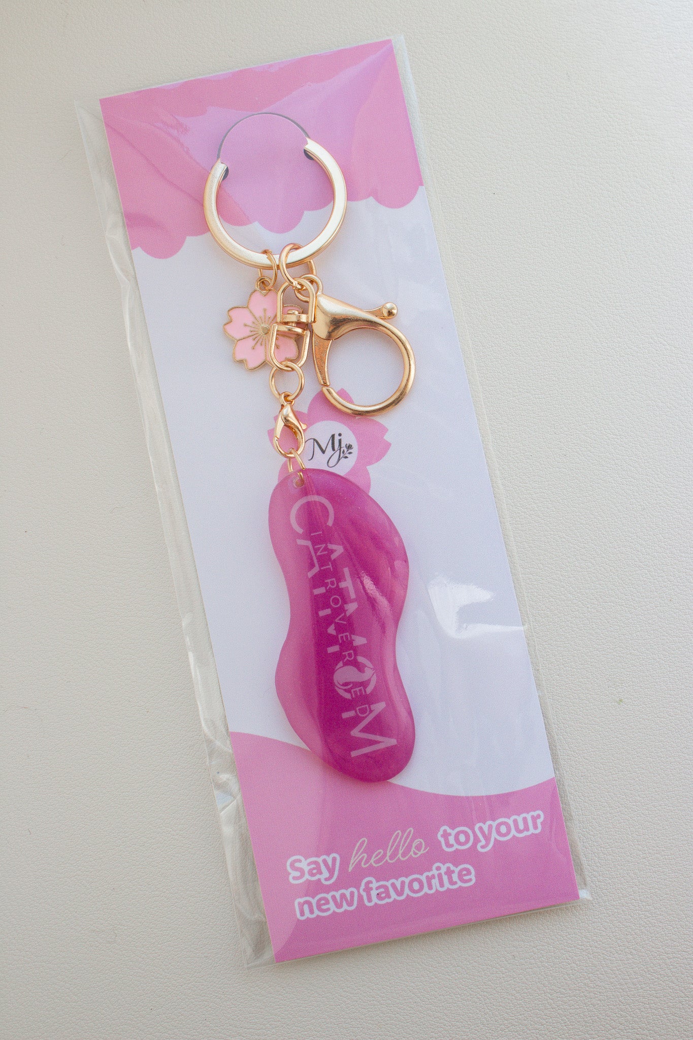 Pinker „Introverted Cat Mom" Schlüsselanhänger aus Schrumpffolie mit Resin-Versiegelung, pinkem Kirschblüten-Charm und goldfarbenem Karabiner, verpackt in transparenter Tüte mit pinker Brandingkarte
