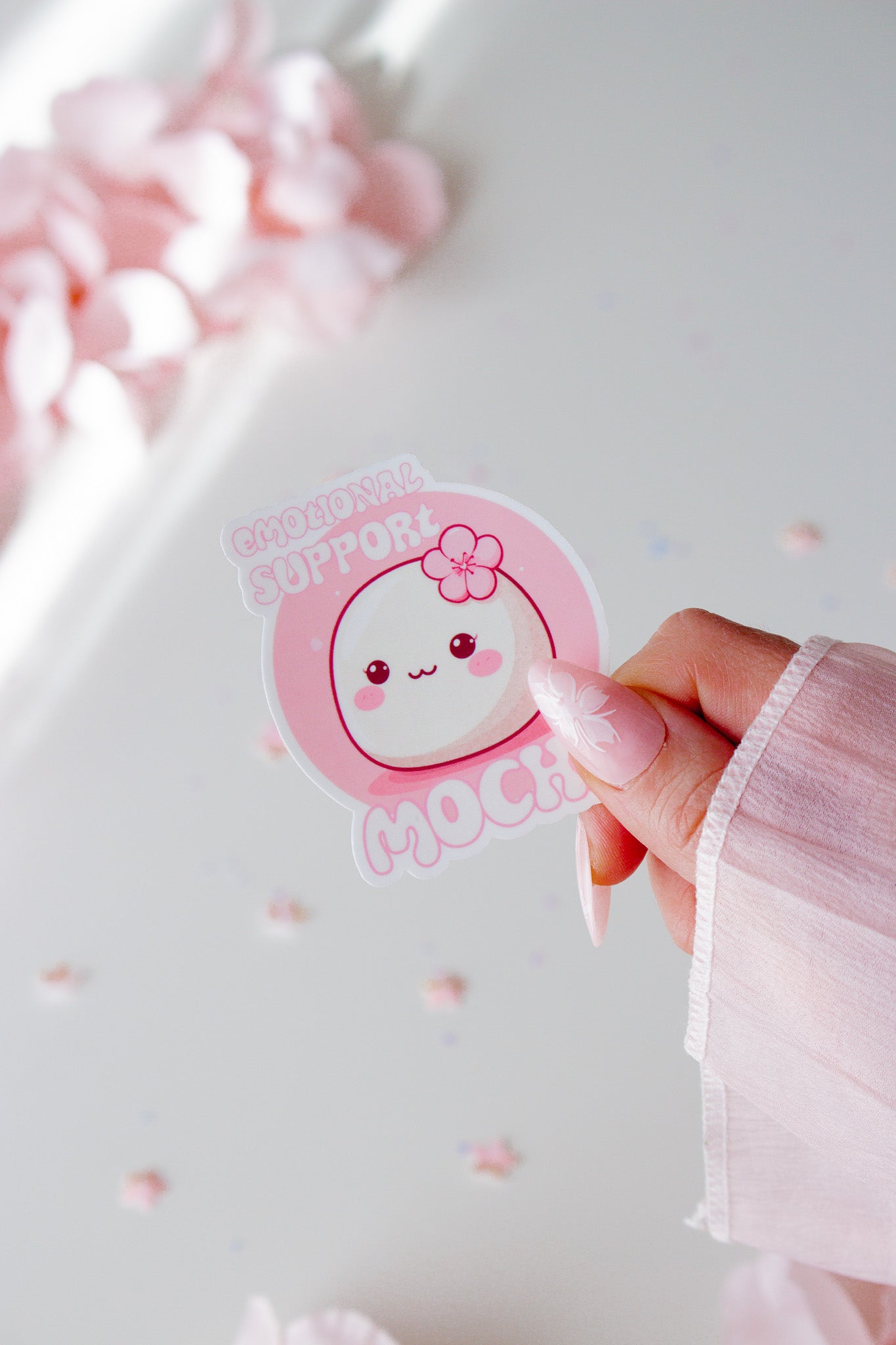 Runder Vinyl Sticker Emotional Support Mochi, niedliches weißes Mochi mit Kirschblüte und rosigen Wangen auf rosa Hintergrund, in der Hand gehalten vor rosa Blüten