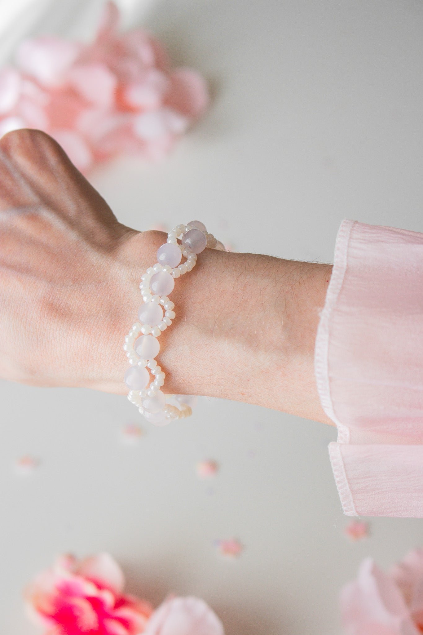 UV-Perlenarmband Weiß-Creme am Handgelenk – vor dem Farbwechsel zu Lila-Violett im Sonnenlicht