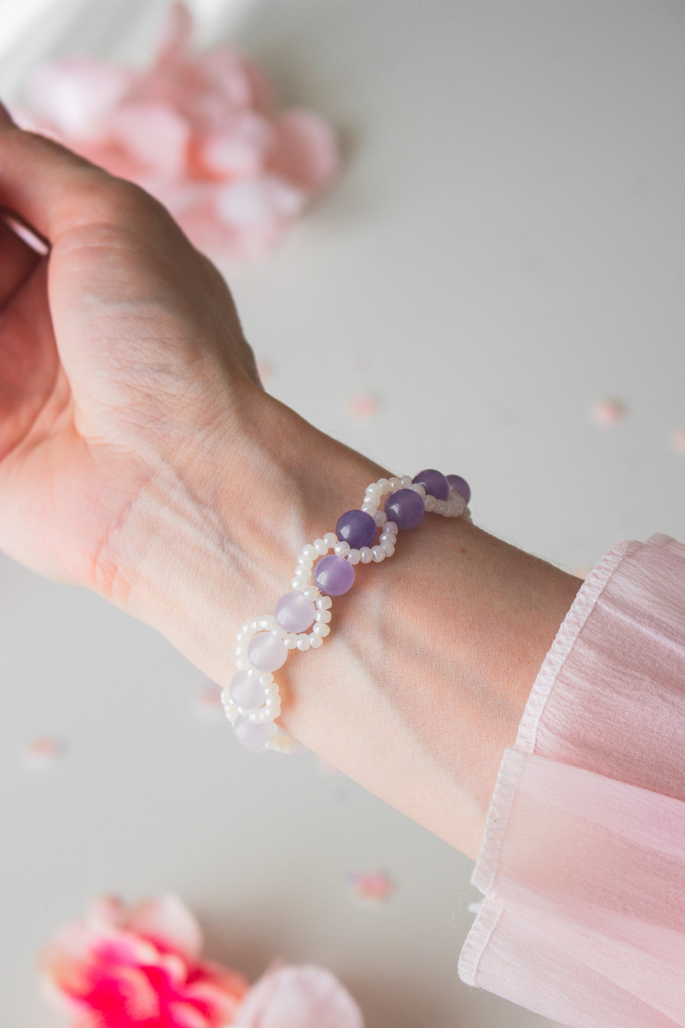 V-Farbwechsel Armband am Handgelenk – große lila Perlen und kleine weiße Acrylperlen im Sonnenlicht aktiviert