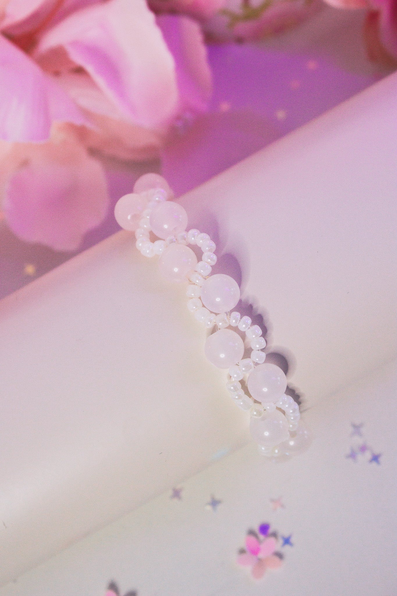 Weißes Perlenarmband auf Nylonband, das im Sonnenlicht zu Rosa-Rot wechselt – handgemacht mit UV-reaktiven Acrylperlen