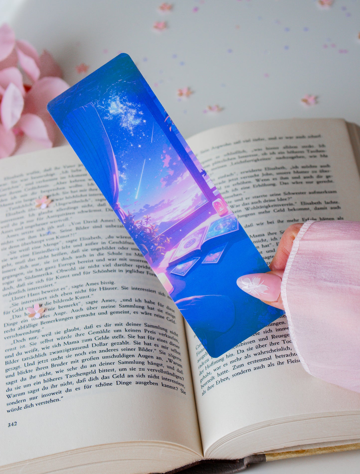 Holografisches Lesezeichen mit mystischen Händen und Sternenhimmel in Blau und Pink, in einem aufgeschlagenen Buch