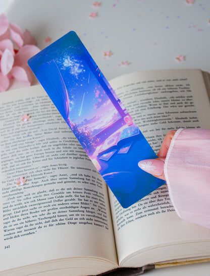 Holografisches Lesezeichen mit mystischen Händen und Sternenhimmel in Blau und Pink, in einem aufgeschlagenen Buch
